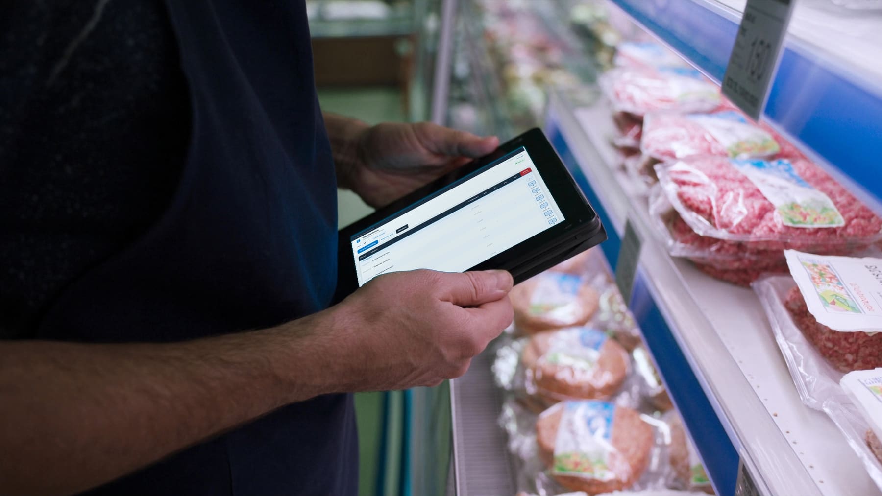 Een medewerker bestelt met Skappie op een tablet aan het vleesschap van de supermarkt.